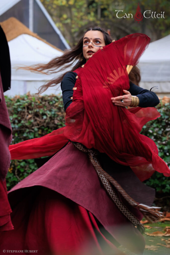 Danse aux éventails lors de la déambulation musicale Beltaine avec échassier