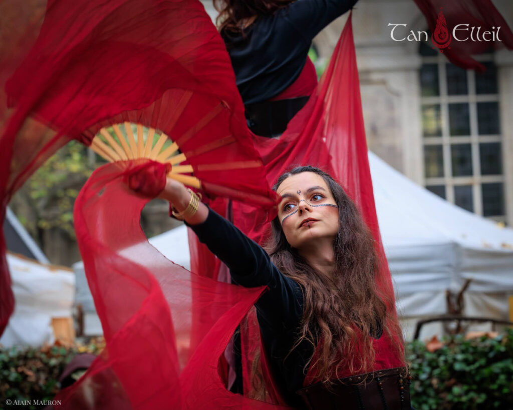 Danse aux éventails lors de la déambulation musicale Beltaine avec échassier